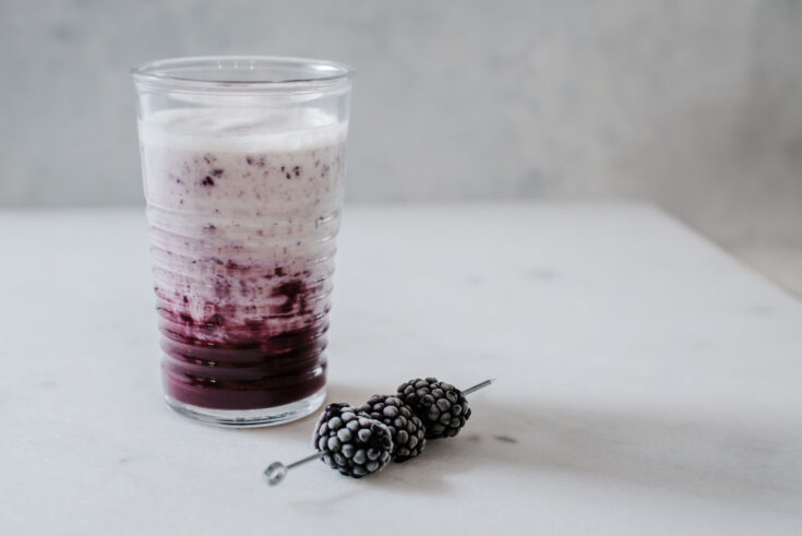 Single glass of fruit smoothie and blackberry garnish